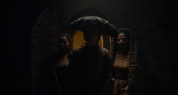 Movie still from “The Green Knight” (2021), directed by David Lowery – A group of women standing next to each other in the dark; Medium shot, Low angle