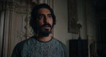 Movie still from “The Green Knight” (2021), directed by David Lowery – A man with long hair and a beard looking to his left; Close Up shot, Low angle