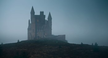 Movie still from “The Green Knight” (2021), directed by David Lowery – A large castle on top of a hill in the fog; Extreme Wide shot, Low angle