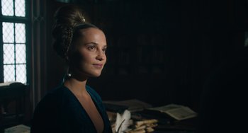 Movie still from “The Green Knight” (2021), directed by David Lowery – A beautiful woman with a bun in a dark room; Close Up shot, Over the shoulder angle