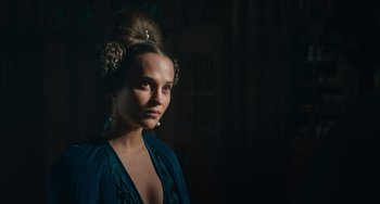 Movie still from “The Green Knight” (2021), directed by David Lowery – A young woman with long hair is posing for a picture; Close Up shot, Over the shoulder angle