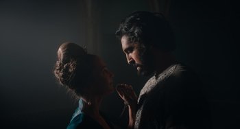 Movie still from “The Green Knight” (2021), directed by David Lowery – A man and a woman are looking at each other in the dark; Medium shot, Low angle