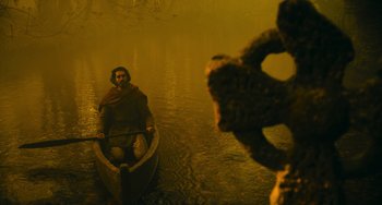 Movie still from “The Green Knight” (2021), directed by David Lowery – A man in a boat on a body of water; Wide shot, Low angle