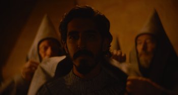 Movie still from “The Green Knight” (2021), directed by David Lowery – A man with a long beard and a man with a pointed hat; Close Up shot, Over the shoulder angle