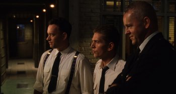 Movie still from “The Green Mile” (1999), directed by Frank Darabont – A group of men standing next to each other in front of a brick wall; Medium shot, Low angle