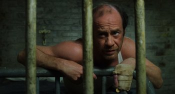 Movie still from “The Green Mile” (1999), directed by Frank Darabont – A man leaning up against a metal fence; Close Up shot, High angle