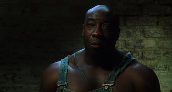 Movie still from “The Green Mile” (1999), directed by Frank Darabont – A man with a beard wearing overalls and looking at the camera; Close Up shot, Low angle