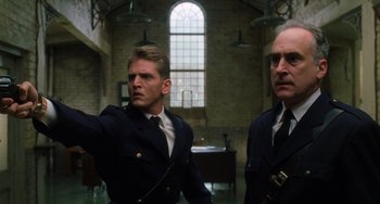 Movie still from “The Green Mile” (1999), directed by Frank Darabont – Two men in uniform standing in front of a brick wall; Medium shot, Low angle