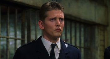 Movie still from “The Green Mile” (1999), directed by Frank Darabont – A man wearing a suit and tie in front of a wall; Close Up shot, Low angle