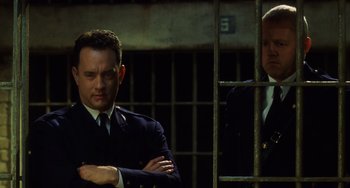 Movie still from “The Green Mile” (1999), directed by Frank Darabont – A man standing next to another man behind bars; Close Up shot, Low angle