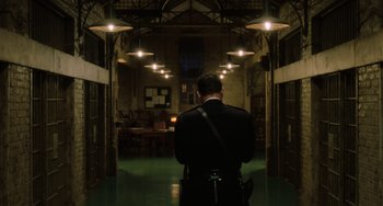 Movie still from “The Green Mile” (1999), directed by Frank Darabont – A man standing in a dark hallway with lights on; Wide shot, Low angle