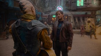 Movie still from “The Guardians of the Galaxy Holiday Special” (2022), directed by James Gunn – A man standing next to an alien on a street; Medium shot, Over the shoulder angle