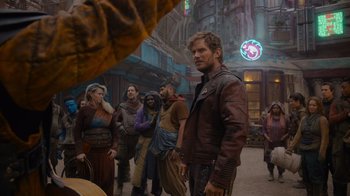 Movie still from “The Guardians of the Galaxy Holiday Special” (2022), directed by James Gunn – A group of people standing around a building; Medium shot, Over the shoulder angle