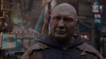 Movie still from “The Guardians of the Galaxy Holiday Special” (2022), directed by James Gunn – A bald man with red eyes is standing outside; Close Up shot, Over the shoulder angle