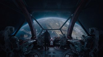 Movie still from “The Guardians of the Galaxy Holiday Special” (2022), directed by James Gunn – A man standing inside of an airplane looking out at the earth; Extreme Wide shot, High angle