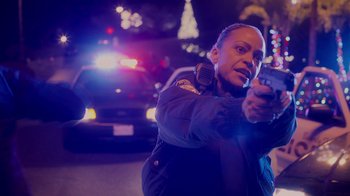 Movie still from “The Guardians of the Galaxy Holiday Special” (2022), directed by James Gunn – A police officer holding a gun while standing in front of a cop car; Close Up shot, Low angle