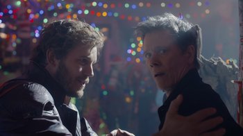 Movie still from “The Guardians of the Galaxy Holiday Special” (2022), directed by James Gunn – Two men standing next to each other in front of lights; Close Up shot, Over the shoulder angle