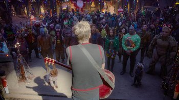 Movie still from “The Guardians of the Galaxy Holiday Special” (2022), directed by James Gunn – A crowd of people standing around a man holding a guitar; Wide shot, Over the shoulder angle
