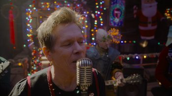 Movie still from “The Guardians of the Galaxy Holiday Special” (2022), directed by James Gunn – A man with a microphone in front of a guitar; Close Up shot, Over the shoulder angle