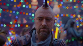 Movie still from “The Guardians of the Galaxy Holiday Special” (2022), directed by James Gunn – A man with a shaved head is standing in front of lights; Close Up shot, Over the shoulder angle