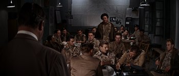 Movie still from “The Guns of Navarone” (1961), directed by J. Lee Thompson – A group of men sitting around a table eating food; Wide shot, High angle