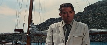 Movie still from “The Guns of Navarone” (1961), directed by J. Lee Thompson – A man wearing a suit and tie standing on a boat; Close Up shot, Low angle
