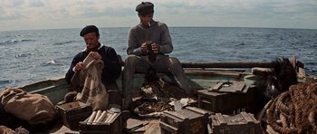 Movie still from “The Guns of Navarone” (1961), directed by J. Lee Thompson – A man sitting on a boat next to another man; Medium shot, High angle