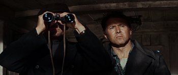 Movie still from “The Guns of Navarone” (1961), directed by J. Lee Thompson – A man looking through binoculars while standing next to another man; Close Up shot, Low angle