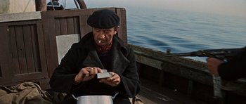 Movie still from “The Guns of Navarone” (1961), directed by J. Lee Thompson – A man sitting on a boat with a cigarette in his mouth; Medium shot, High angle