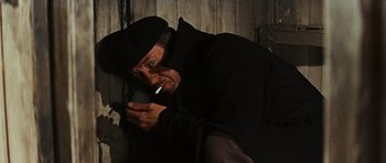Movie still from “The Guns of Navarone” (1961), directed by J. Lee Thompson – An old man smoking a cigarette while leaning against a wall; Medium shot, Low angle