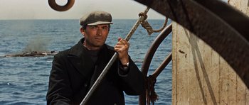 Movie still from “The Guns of Navarone” (1961), directed by J. Lee Thompson – A man holding a rope on a boat in the ocean; Medium shot, Low angle