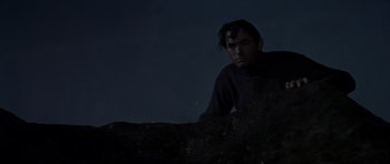 Movie still from “The Guns of Navarone” (1961), directed by J. Lee Thompson – A man standing in front of a rock wall at night; Medium shot, Low angle