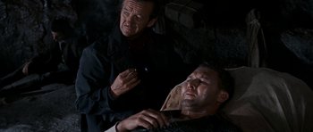 Movie still from “The Guns of Navarone” (1961), directed by J. Lee Thompson – Two men are sitting in a dark room; Medium shot, High angle