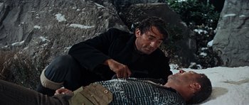 Movie still from “The Guns of Navarone” (1961), directed by J. Lee Thompson – A man in a black jacket is cutting a man's face; Medium shot, High angle