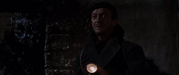 Movie still from “The Guns of Navarone” (1961), directed by J. Lee Thompson – A man holding a flashlight while standing next to a brick wall; Close Up shot, Low angle