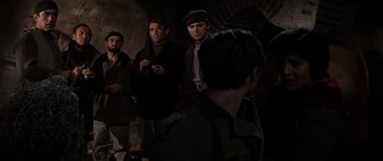 Movie still from “The Guns of Navarone” (1961), directed by J. Lee Thompson – A group of men standing next to each other in a dark room; Medium shot, Over the shoulder angle