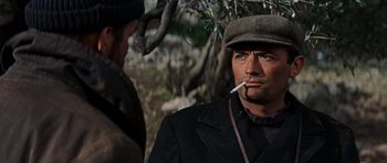 Movie still from “The Guns of Navarone” (1961), directed by J. Lee Thompson – A man smoking a cigarette while wearing a hat; Close Up shot, Over the shoulder angle