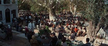 Movie still from “The Guns of Navarone” (1961), directed by J. Lee Thompson – A crowd of people sitting at tables under a tree; Extreme Wide shot, High angle
