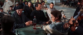 Movie still from “The Guns of Navarone” (1961), directed by J. Lee Thompson – A group of people sitting at a table with drinks; Medium shot, Over the shoulder angle