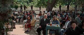 Movie still from “The Guns of Navarone” (1961), directed by J. Lee Thompson – A group of people sitting at tables under a tree; Wide shot, High angle