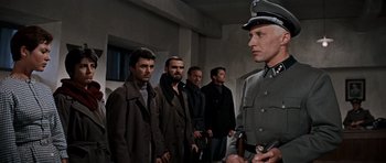 Movie still from “The Guns of Navarone” (1961), directed by J. Lee Thompson – A group of men standing next to each other in a room; Medium shot, Low angle