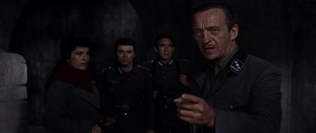 Movie still from “The Guns of Navarone” (1961), directed by J. Lee Thompson – A group of men standing next to each other in a dark room; Medium shot, Low angle