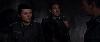 Movie still from “The Guns of Navarone” (1961), directed by J. Lee Thompson – A man and a woman standing next to each other; Medium shot, Low angle