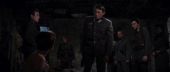 Movie still from “The Guns of Navarone” (1961), directed by J. Lee Thompson – A group of men standing next to each other in a room; Medium shot, Low angle