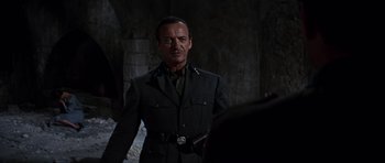 Movie still from “The Guns of Navarone” (1961), directed by J. Lee Thompson – A man in a military uniform standing next to a wall; Medium shot, Over the shoulder angle