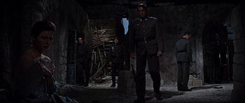 Movie still from “The Guns of Navarone” (1961), directed by J. Lee Thompson – A group of men standing next to each other in a building; Wide shot, Low angle