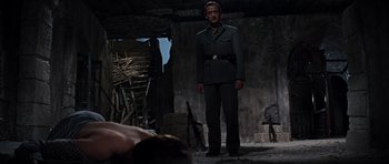 Movie still from “The Guns of Navarone” (1961), directed by J. Lee Thompson – A man in a uniform standing next to a woman in a bed; Medium shot, Low angle