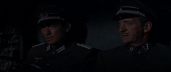 Movie still from “The Guns of Navarone” (1961), directed by J. Lee Thompson – Two men in uniforms are standing next to each other in the dark; Close Up shot, High angle