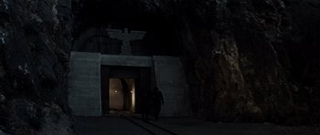 Movie still from “The Guns of Navarone” (1961), directed by J. Lee Thompson – Two people walking in front of an entrance to a cave; Wide shot, Low angle