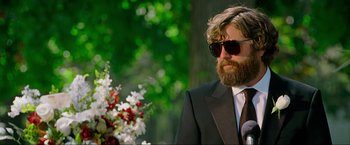 Movie still from “The Hangover Part III” (2013), directed by Todd Phillips – A man in a suit and sunglasses with a flower bouquet; Medium shot, Low angle